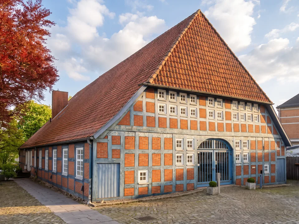 Das Haus Clüver in Achim, ein langes Fachwerkhaus mit rotem Backstein, blauen Balken und großem Dielentor