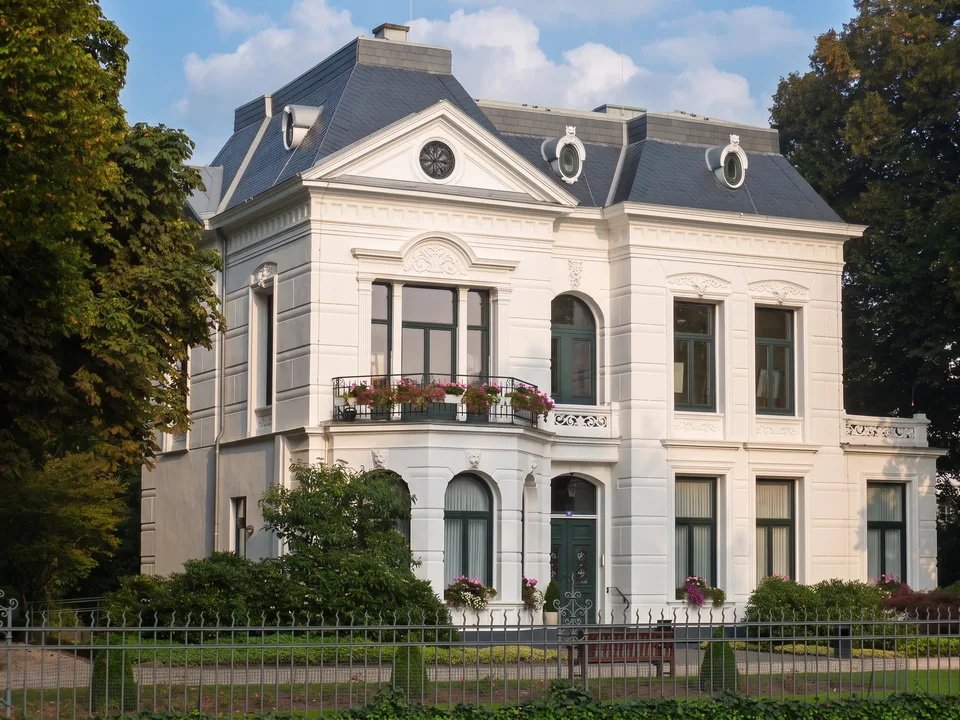 Die weiße klassizistische Villa van Delden in Ahaus mit grauem Mansarddach, Balkon mit Blumen und schmiedeeisernem Zaun