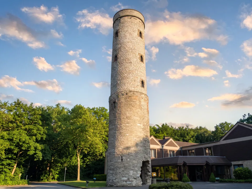 Der runde Bruchsteinturm der Soestwarte auf dem Höxberg bei Beckum zwischen grünen Bäumen