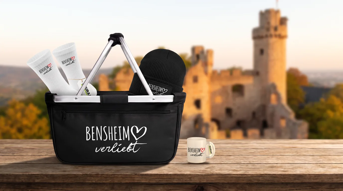 Schwarzer Einkaufskorb Bensheim verliebt mit Beanie und Socken, daneben die Kaffeetasse, auf einem Holztisch vor dem Auerbacher Schloss