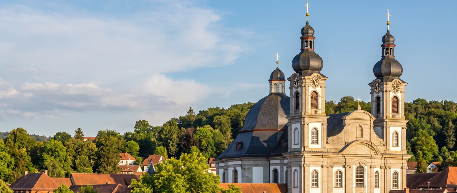 Die barocke Peterskirche in Bruchsal mit zwei Zwiebeltürmen über den Dächern der Stadt im Abendlicht