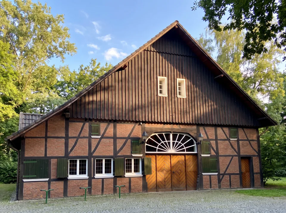 Der Dorfschultenhof in Datteln, ein Fachwerkhaus mit dunklem Holzgiebel, Backstein, grünen Fensterläden und großem Rundbogentor
