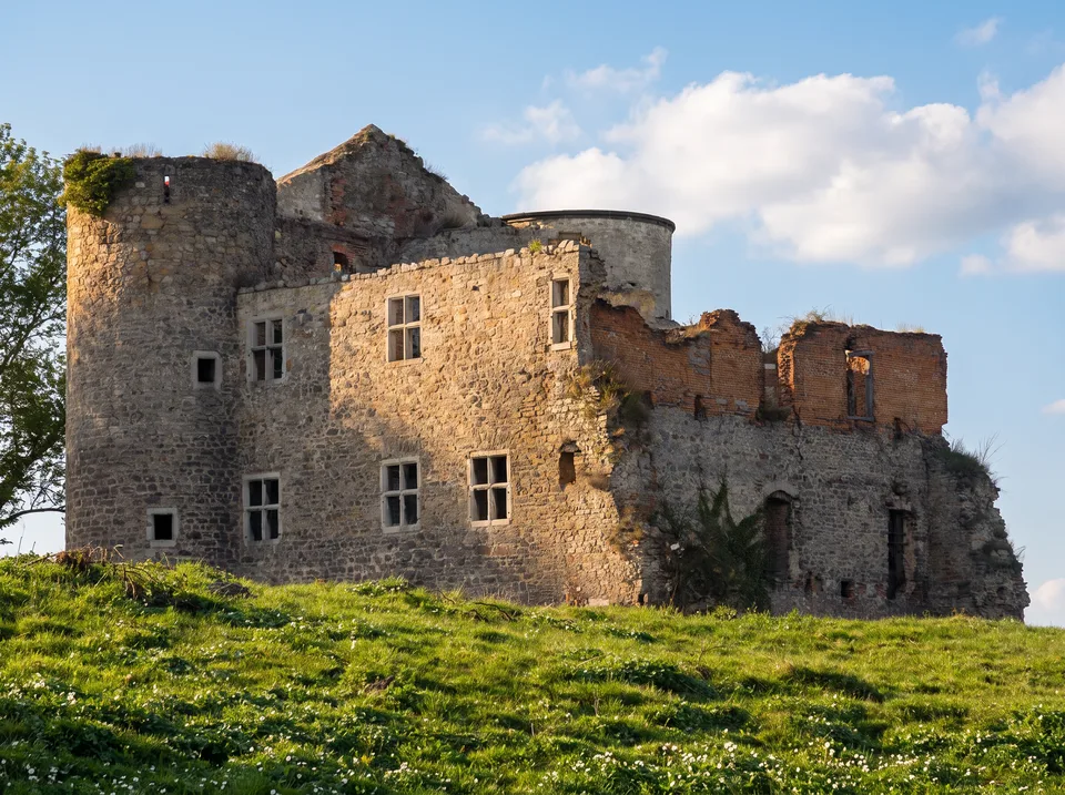 Ruine der Nothberger Burg in Eschweiler aus grauem Bruchstein mit runden Ecktürmen auf einer grünen Wiese