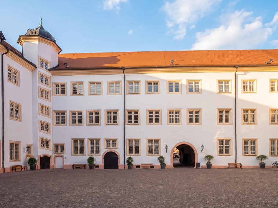 Der weiße Innenhof des Markgräflichen Schlosses Ettlingen mit dreigeschossigen Flügeln, rotem Ziegeldach und Eckturm mit Schieferhaube