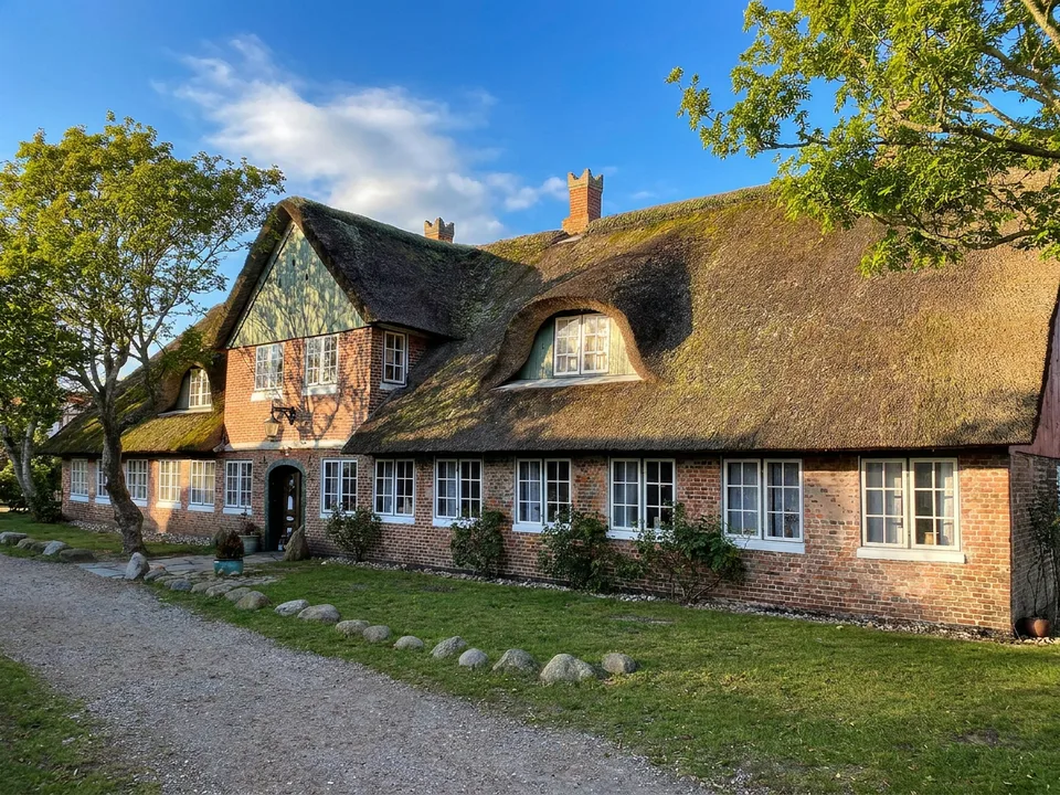 Langes reetgedecktes Backsteinhaus mit Gauben und weißen Sprossenfenstern in Sønderho auf Fanø