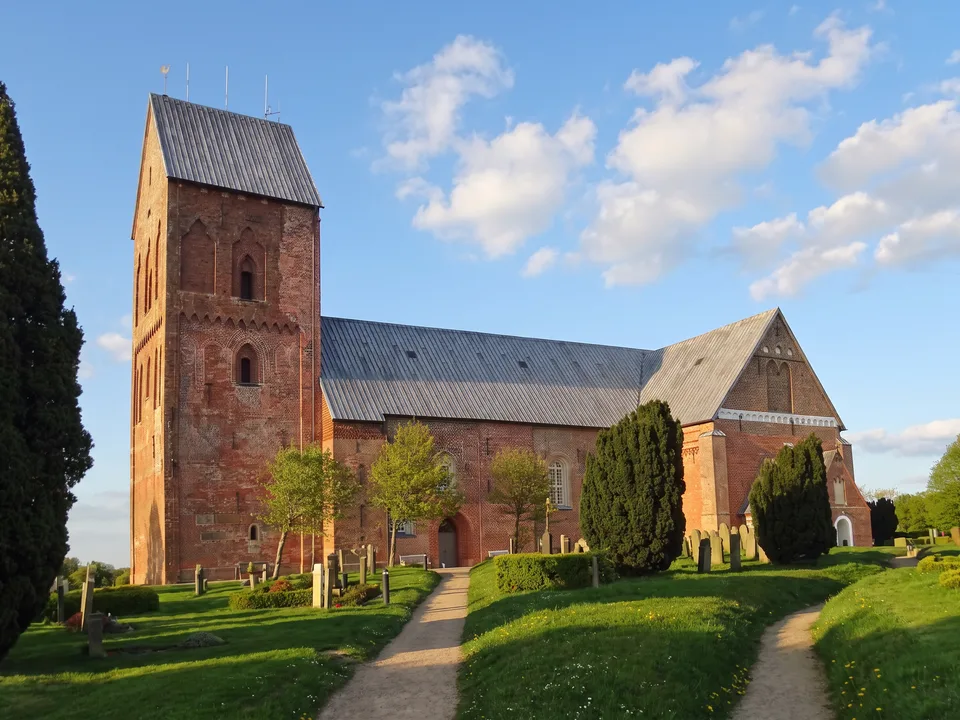 Backsteinkirche St. Johannis in Nieblum auf Föhr mit wuchtigem Westturm und Friedhof im Abendlicht