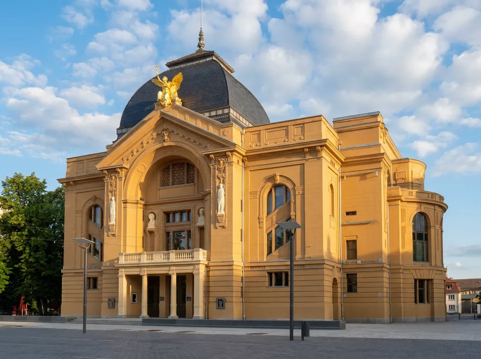 Das ockerfarbene Theater Gera mit dunkler Kuppel und goldener Genius-Figur