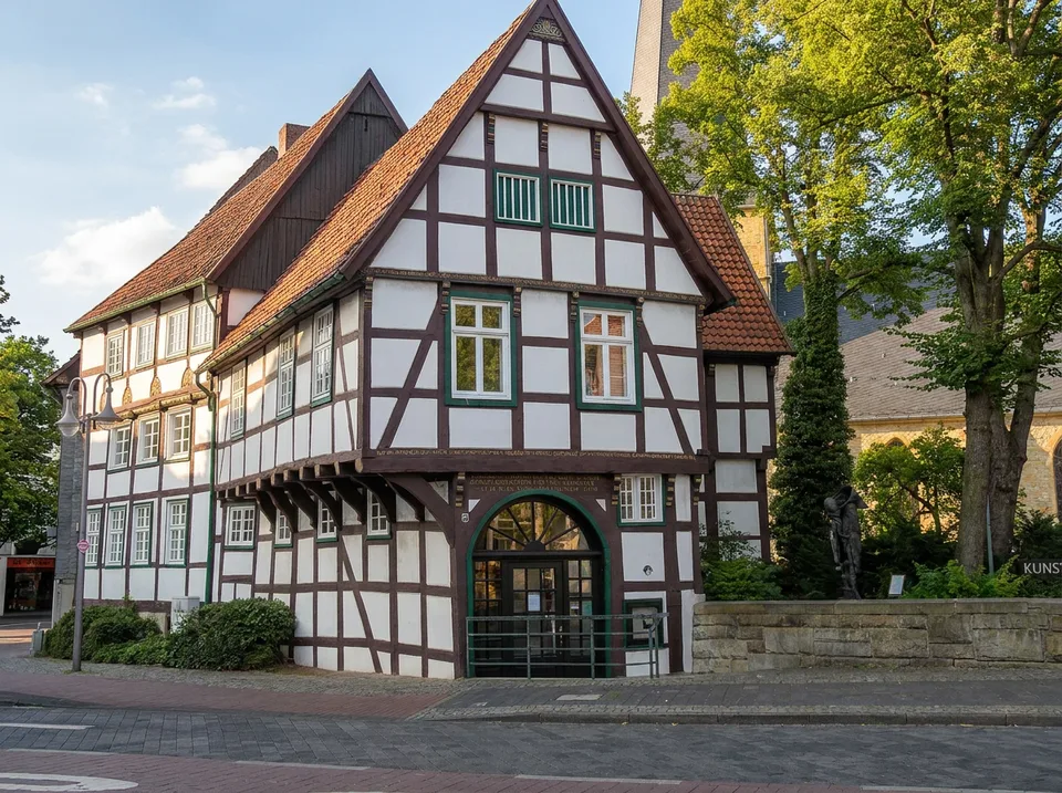 Weißes Fachwerk-Giebelhaus Veerhoffhaus mit grünem Torbogen am Alten Kirchplatz in Gütersloh