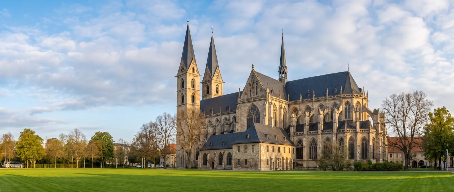 Der gotische Dom St. Stephanus und St. Sixtus in Halberstadt mit zwei spitzen Westtürmen und Strebewerk am grünen Domplatz