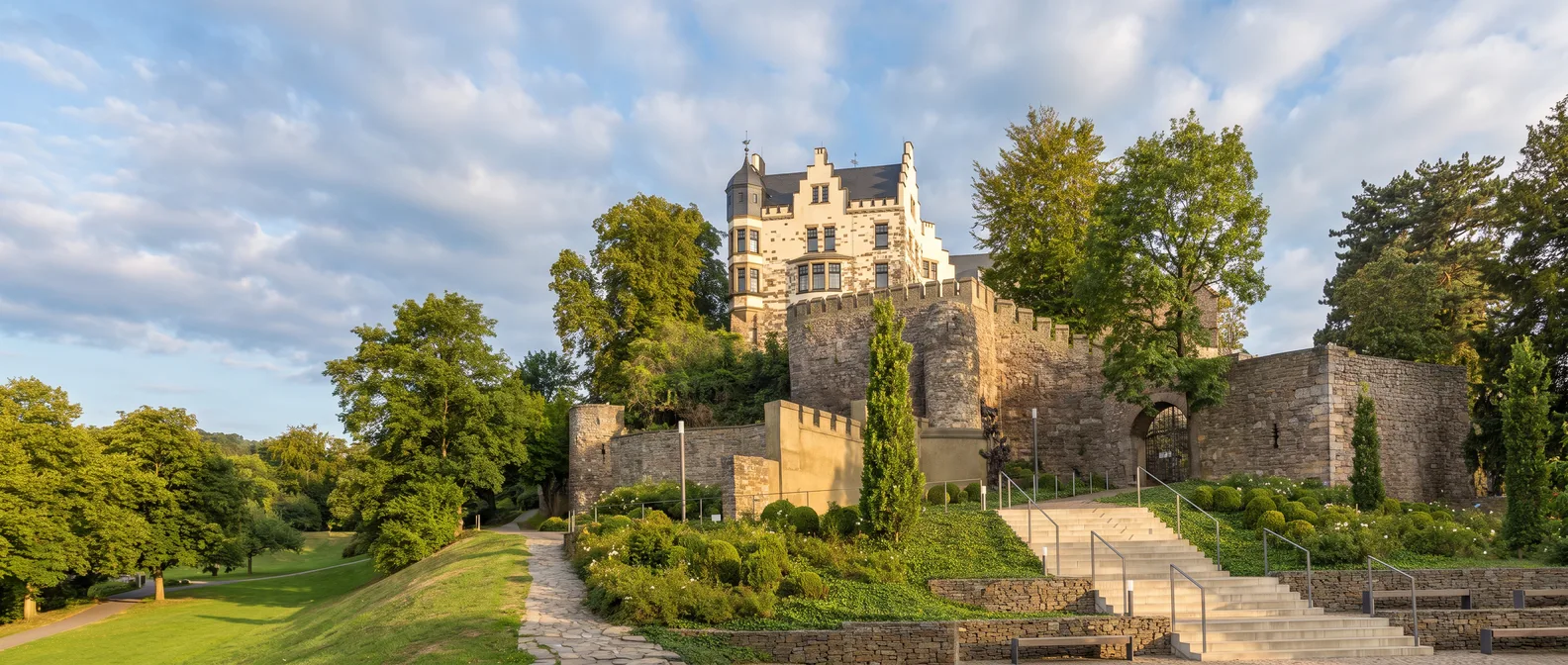 Burg Rode in Herzogenrath mit Treppengiebeln, Eckturm und zinnenbewehrter Mauer über einer breiten Treppe im Abendlicht