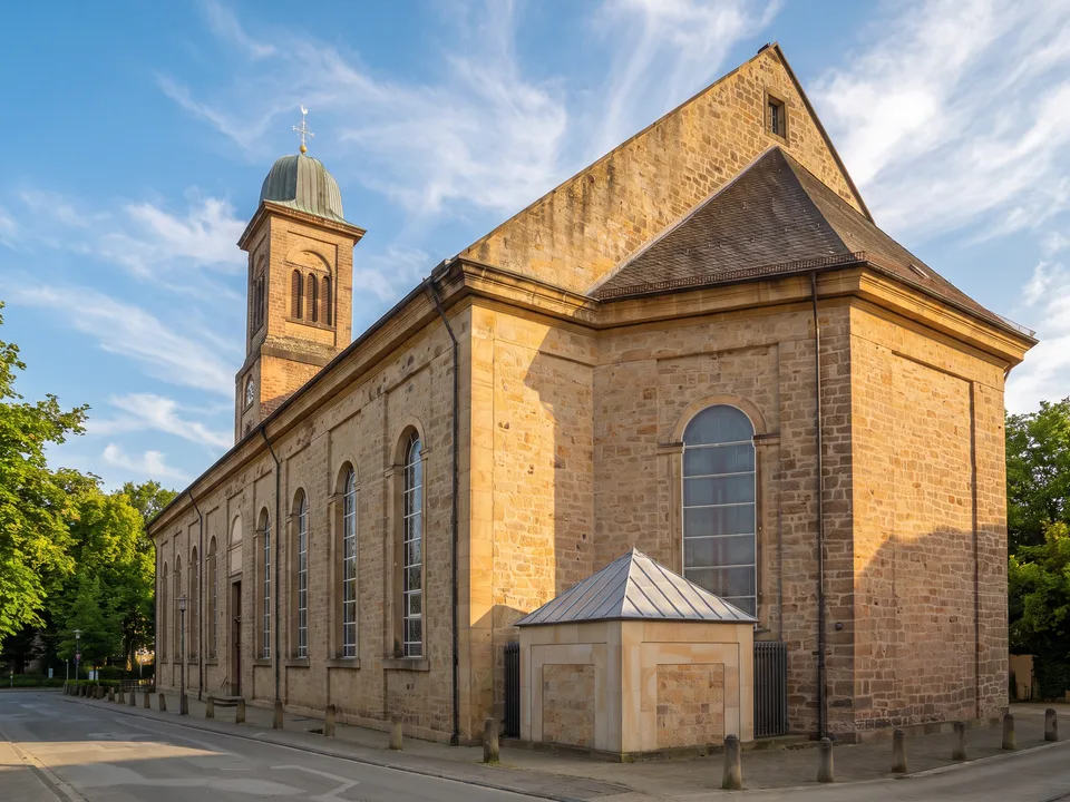 Katholische Kirche St. Mauritius in Ibbenbüren aus hellem Sandstein mit hohen Rundbogenfenstern und Turm mit grüner Kupferhaube