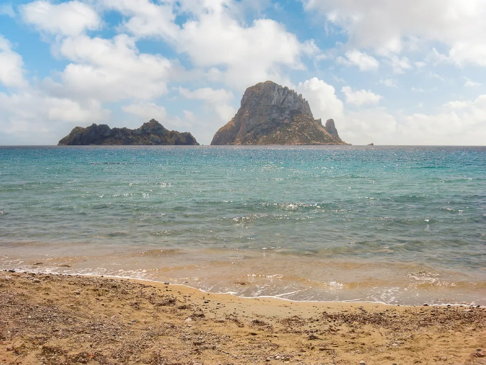 Die Felseninsel Es Vedrà und die kleinere Insel Es Vedranell vor dem Strand von Cala d’Hort auf Ibiza