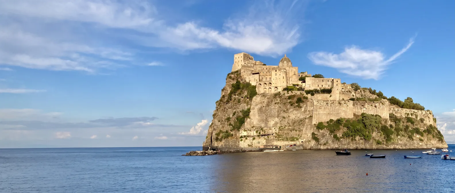 Das Castello Aragonese auf seinem Felsen vor Ischia Ponte im warmen Abendlicht über dem ruhigen Meer