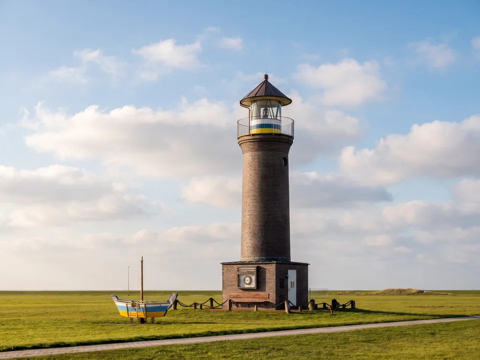 Kleiner Backstein-Leuchtturm Memmertfeuer auf Juist mit weißem Laternenhaus auf einer grünen Wiese