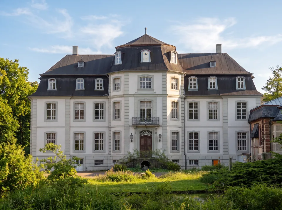 Das helle spätbarocke Herrenhaus von Schloss Türnich in Kerpen mit Mansarddach im Sonnenlicht