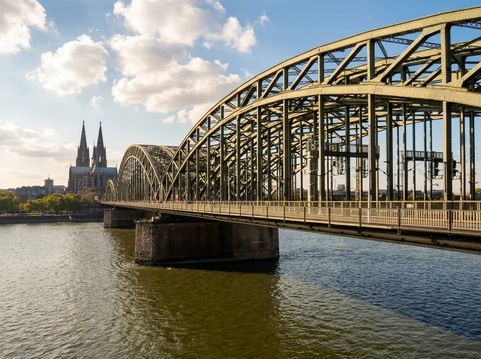 Grüne Stahlbögen der Hohenzollernbrücke über dem Rhein, im Hintergrund der Kölner Dom