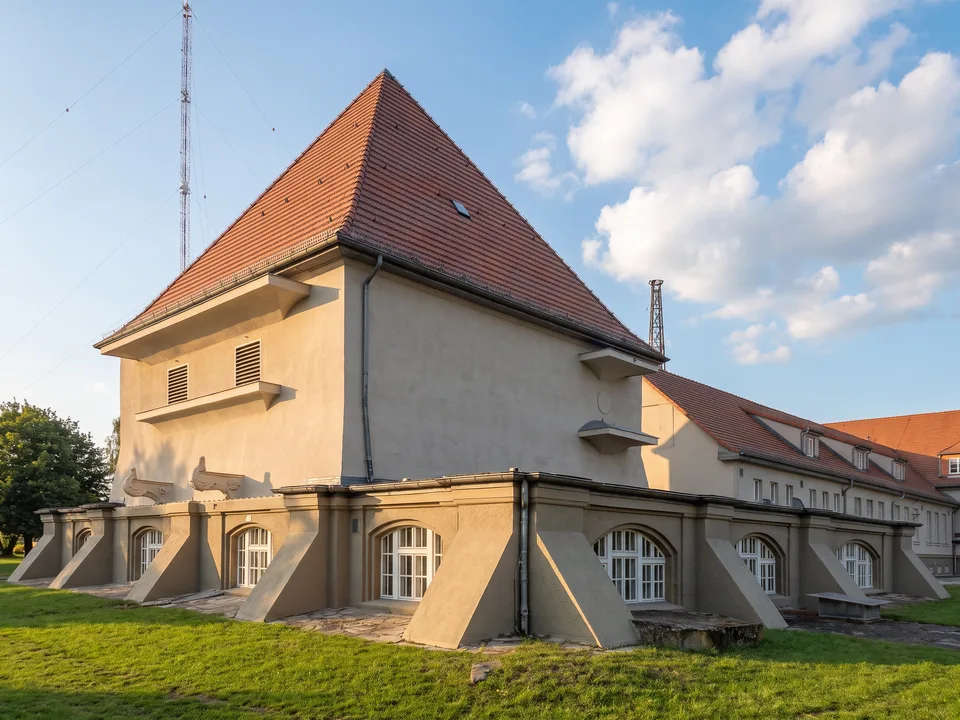 Das historische Senderhaus 1 auf dem Funkerberg in Königs Wusterhausen mit hohem rotem Walmdach, dahinter ein Sendemast