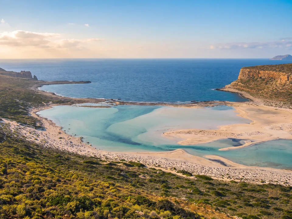 Blick vom Hang auf die türkisfarbene Lagune von Balos mit weißen Sandbänken und dem Kap Tigani