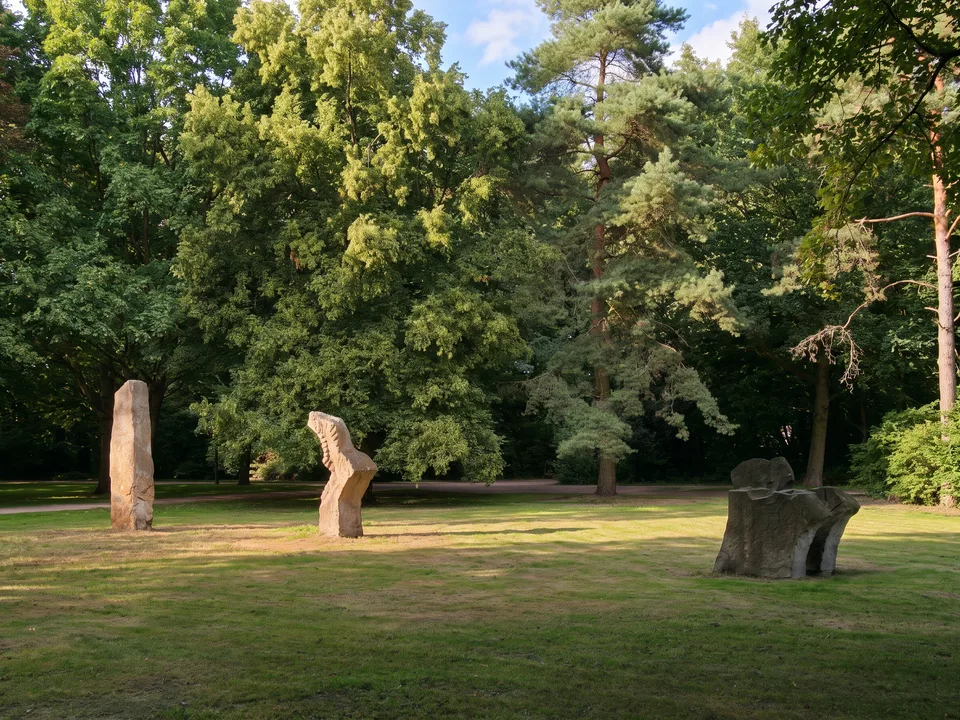 Steinskulpturen auf der Wiese im Stadtpark Langenhagen zwischen alten Bäumen