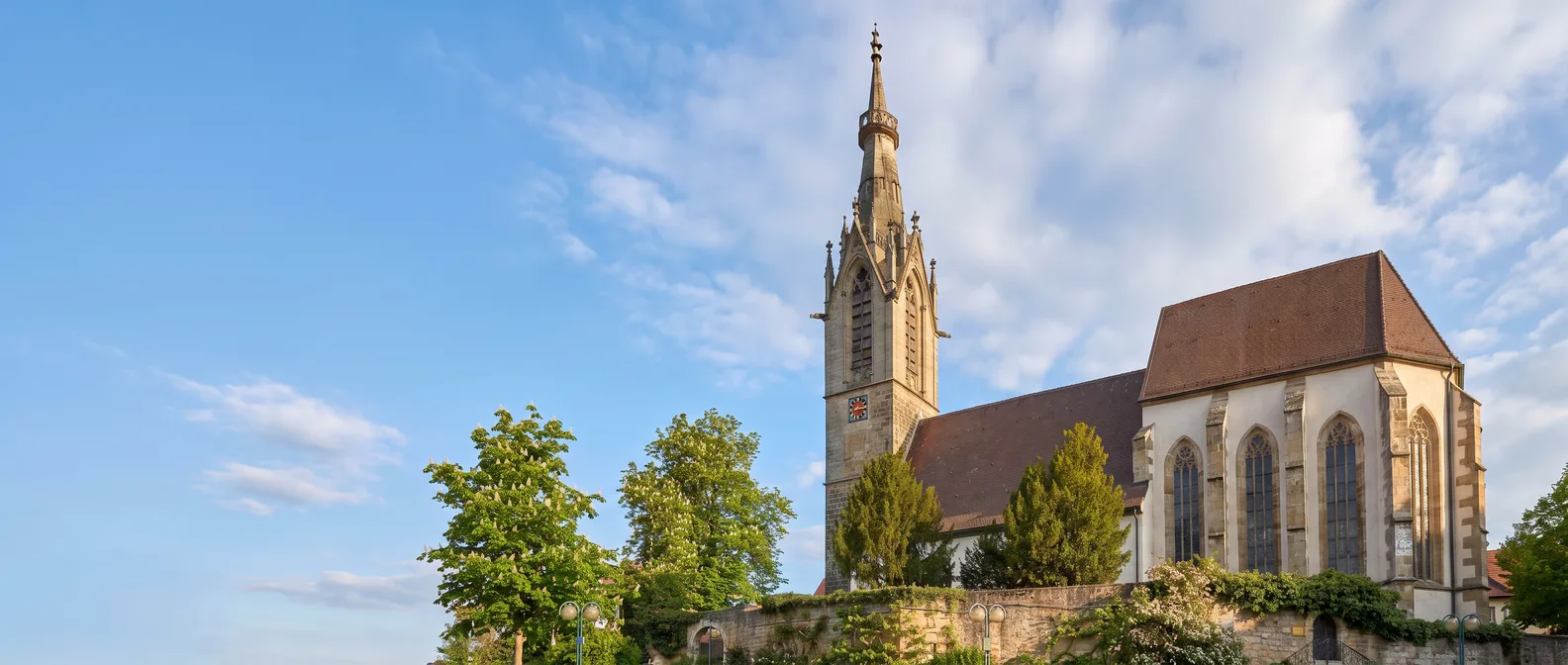 Die Stephanuskirche in Echterdingen mit hohem Sandsteinturm und gotischem Chor unter blauem Himmel