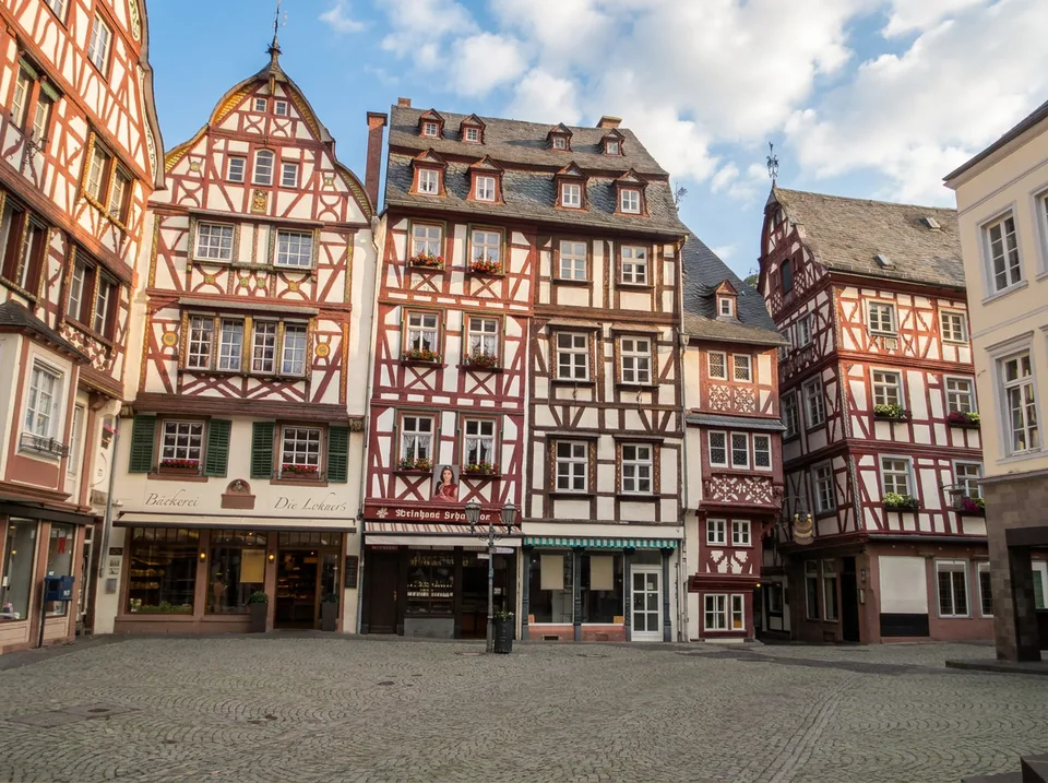 Marktplatz von Bernkastel-Kues mit rot-weißen Giebelfachwerkhäusern und Kopfsteinpflaster in der Nachmittagssonne