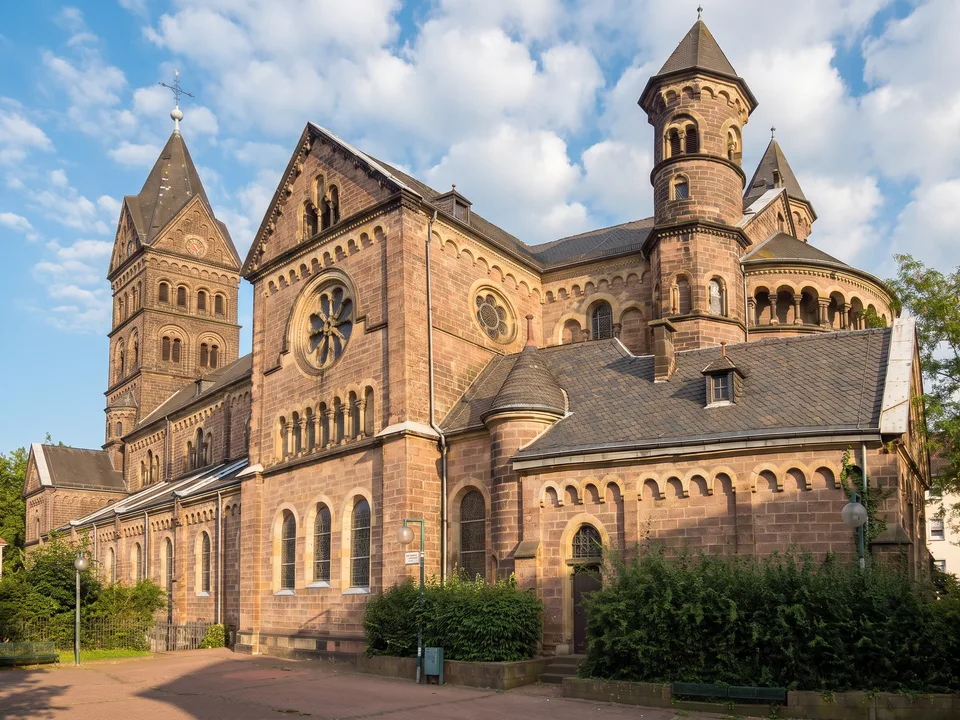 Die neoromanische Kirche St. Marien in Neunkirchen aus rotbraunem Sandstein mit Turm, Rosette und Treppentürmchen