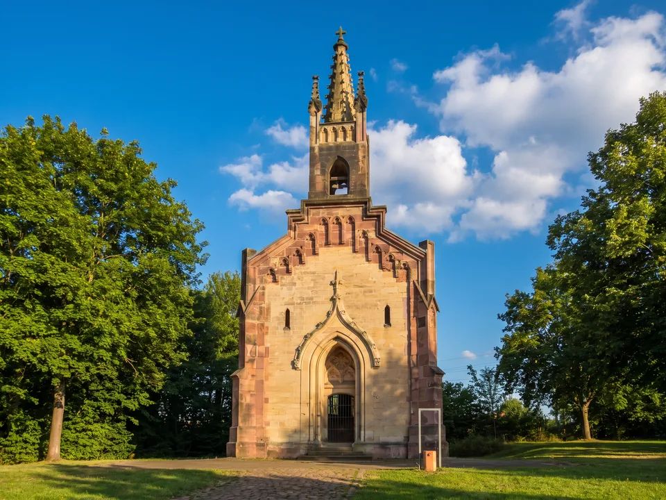 Die neugotische Stummsche Kapelle aus Sandstein mit filigranem Glockentürmchen zwischen grünen Bäumen