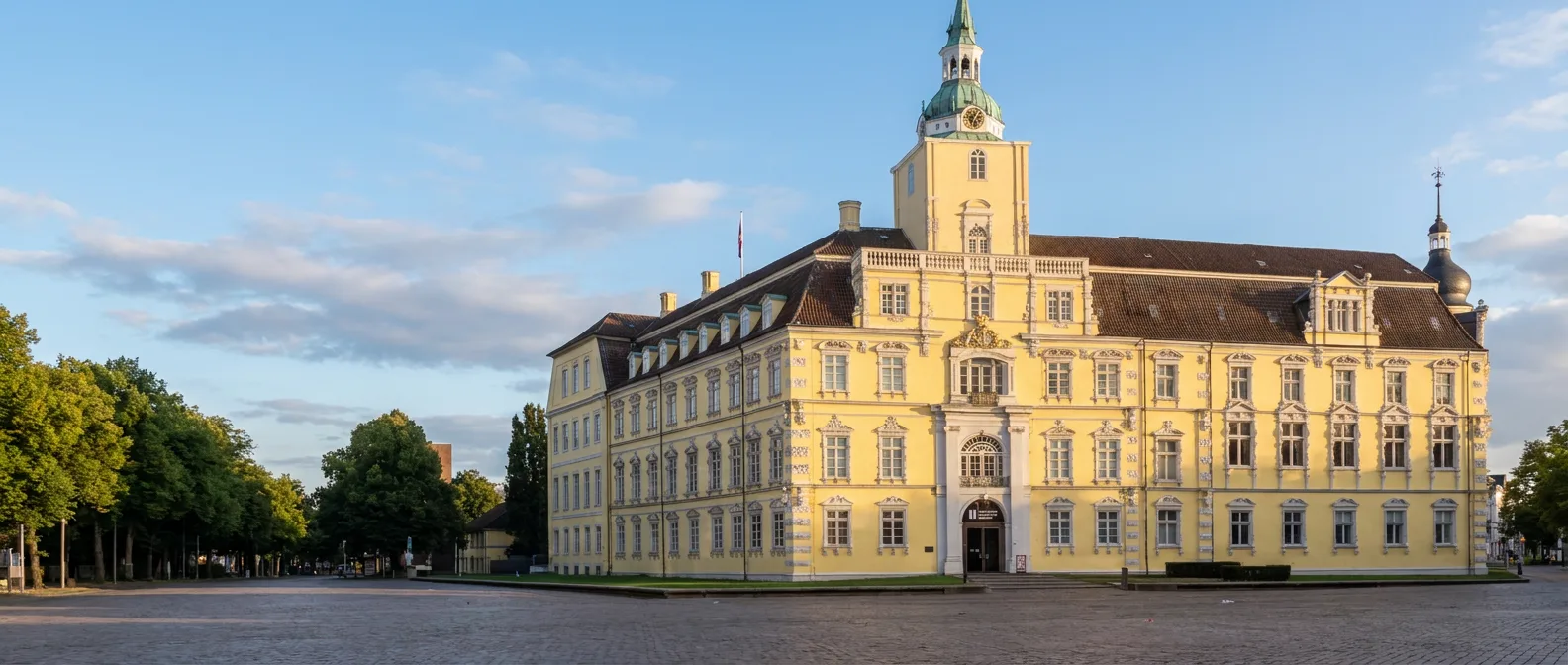 Das gelbe Oldenburger Schloss mit Uhrturm und grüner Kuppel am Schlossplatz im Abendlicht