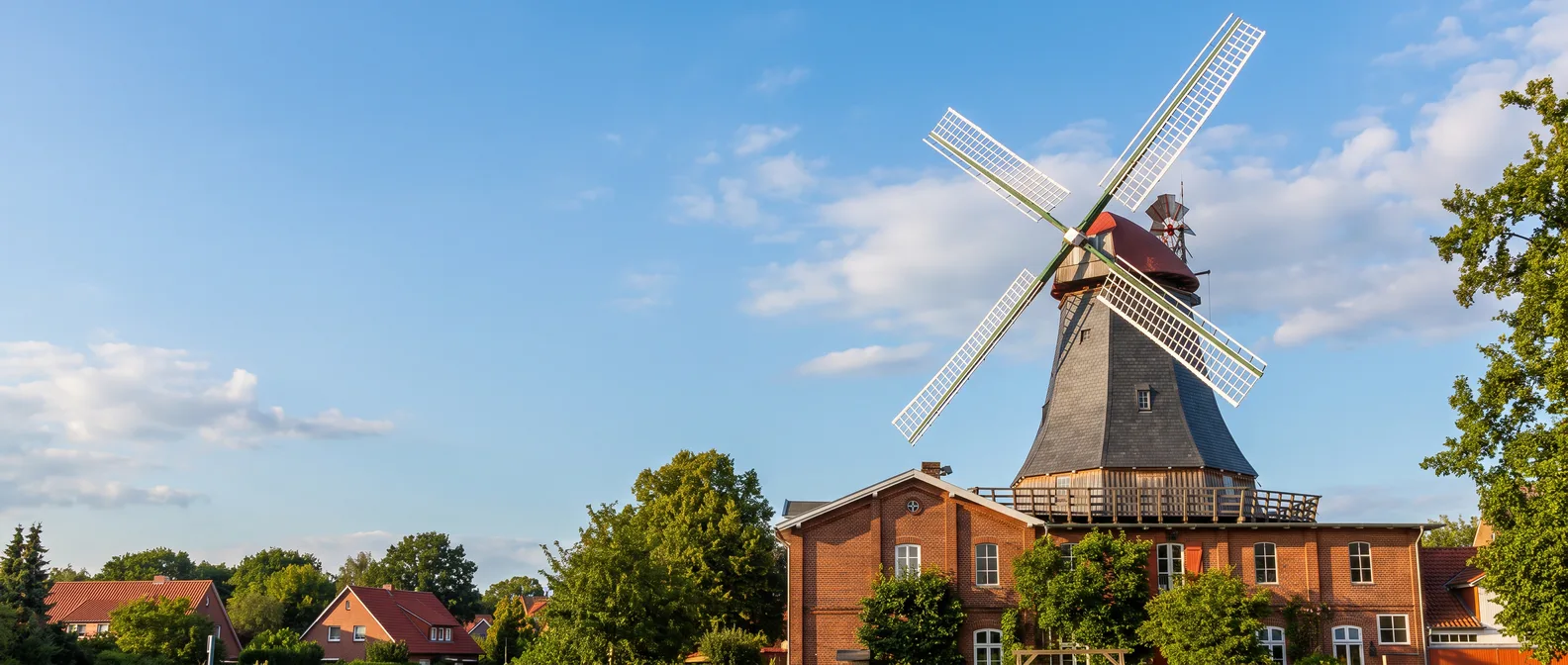 Die Mühle von Rönn in Osterholz-Scharmbeck, ein Galerieholländer mit weißen Flügeln auf rotem Backsteinbau, unter blauem Himmel