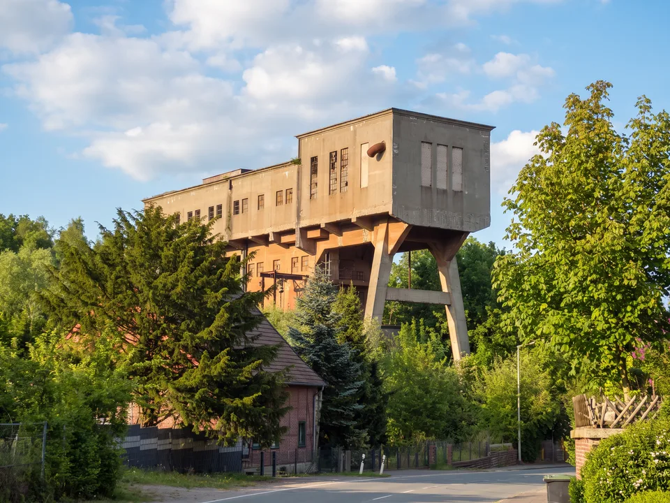 Die hoch aufgeständerte Brecheranlage aus Beton am Besucherbergwerk Kleinenbremen zwischen grünen Bäumen