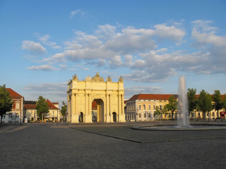 Das Brandenburger Tor am Luisenplatz in Potsdam mit Springbrunnen bei Sonnenschein