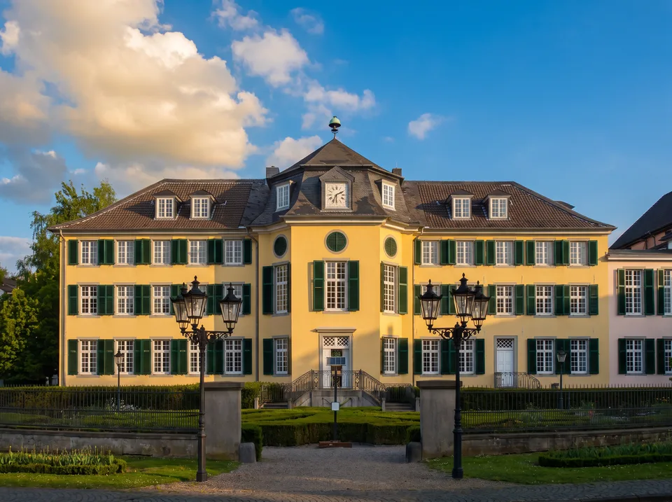 Gelbes barockes Herrenhaus Cromford in Ratingen mit grünen Fensterläden und Uhr im Mansarddach