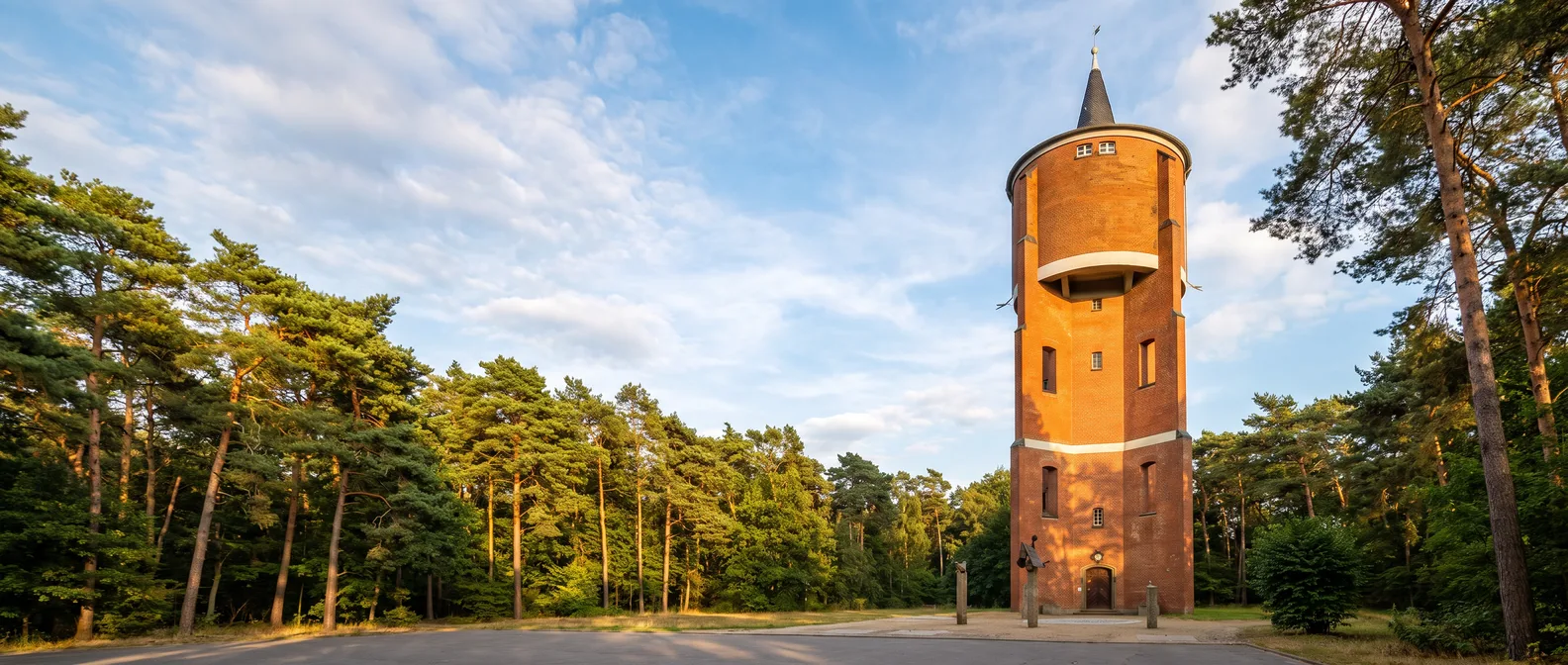 Der Wasserturm aus rotem Backstein in Rodgau-Jügesheim zwischen Kiefern im Abendlicht