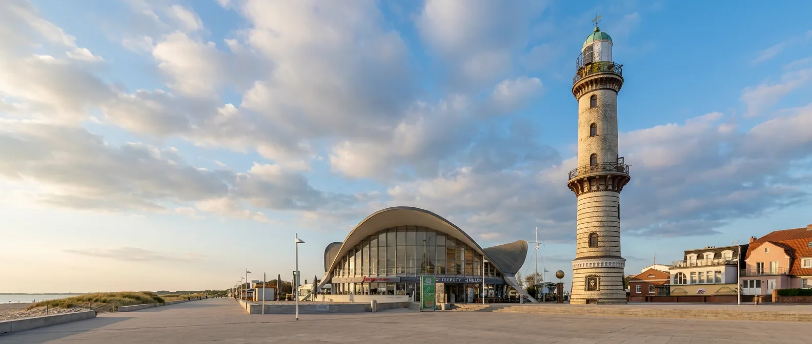 Leuchtturm Warnemünde und der Teepott mit geschwungenem Dach an der Strandpromenade im Abendlicht