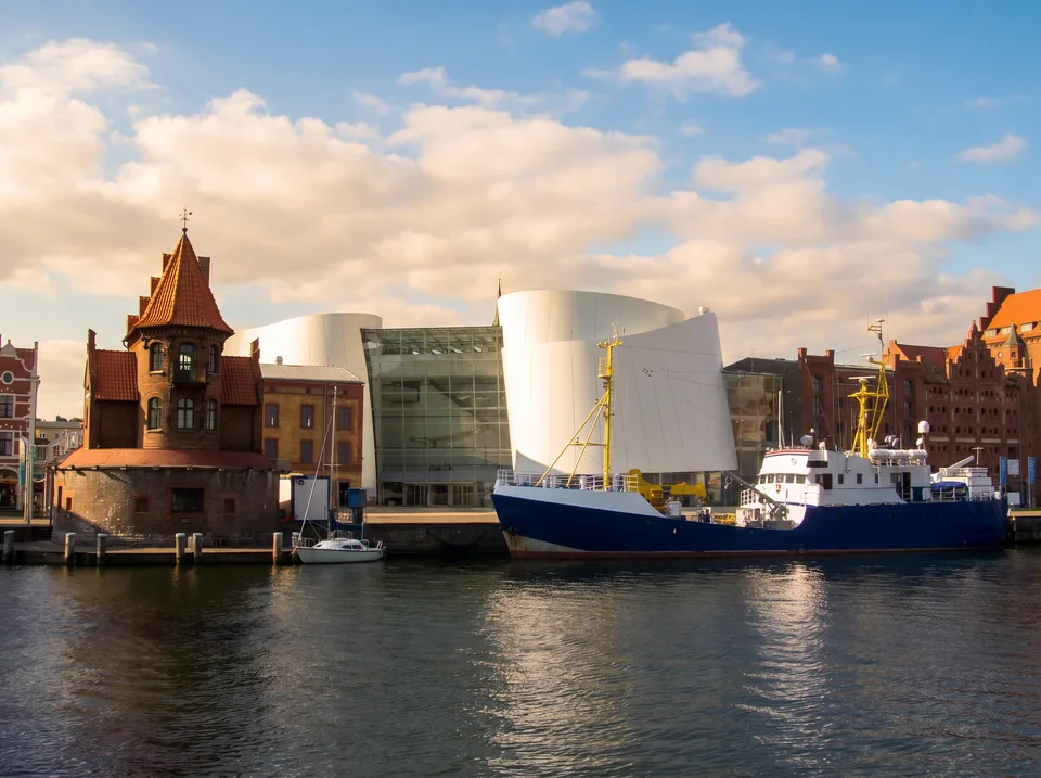 Der Stralsunder Hafen mit dem Backstein-Lotsenhaus, dem weißen Ozeaneum und einem Schiff am Kai