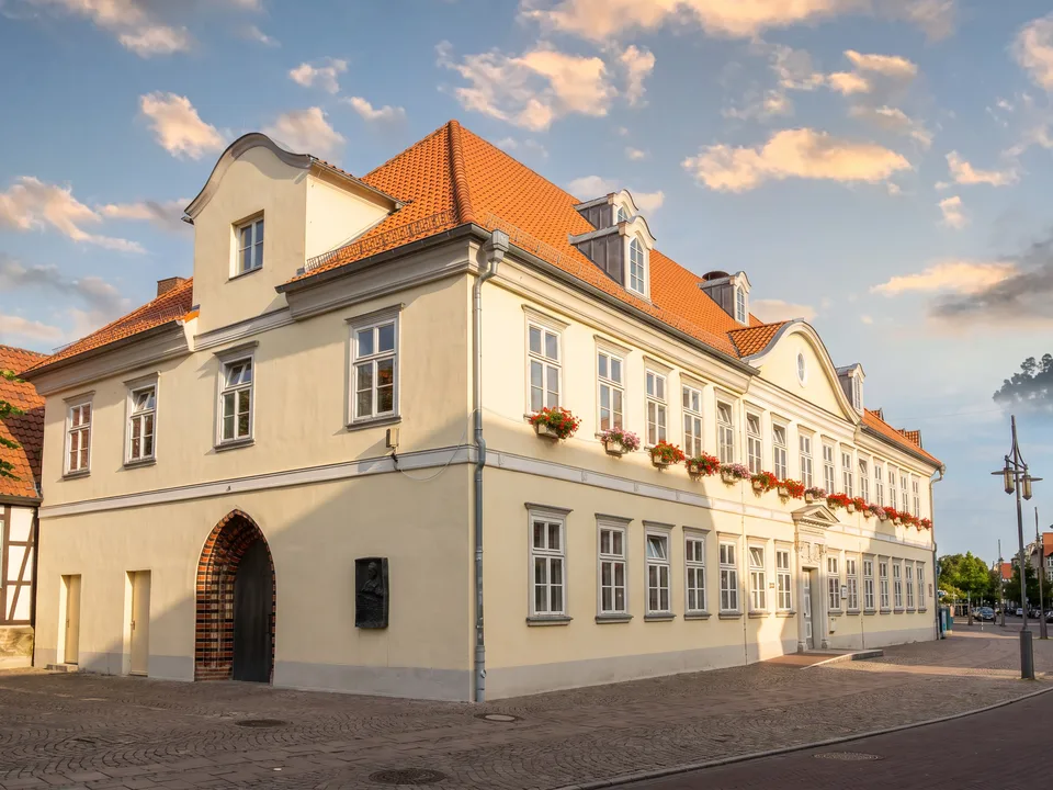 Das hellgelbe Alte Rathaus in Uelzen mit orangefarbenem Ziegeldach, Gauben und Blumenkästen