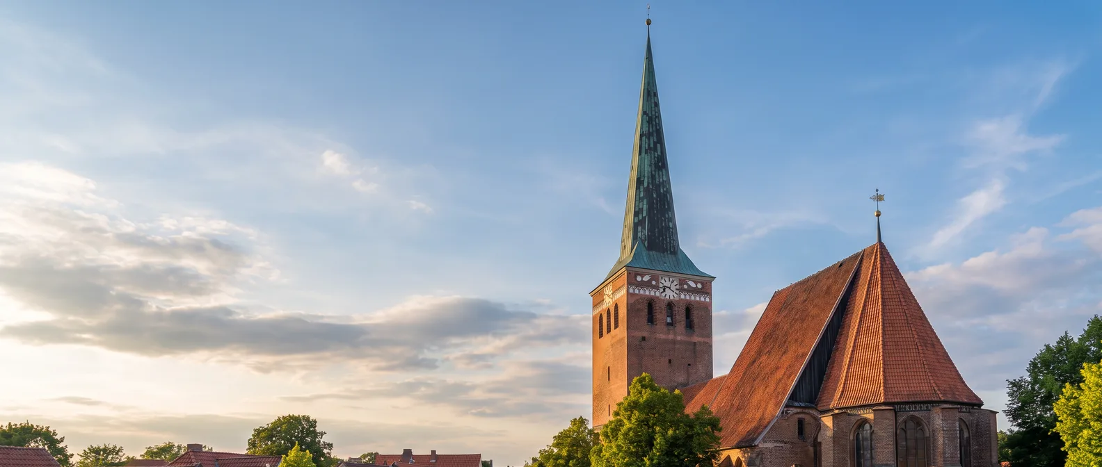 Die gotische St.-Marien-Kirche in Uelzen mit Backsteinturm, grüner Kupferspitze und steilem Ziegeldach über den Dächern der Altstadt