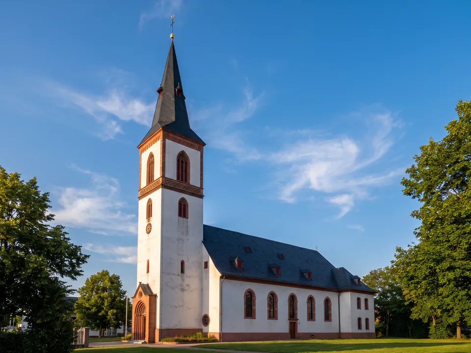 Die Marienkirche in Viernheim mit weißem Turm, roten Sandsteinkanten und spitzem Schieferhelm