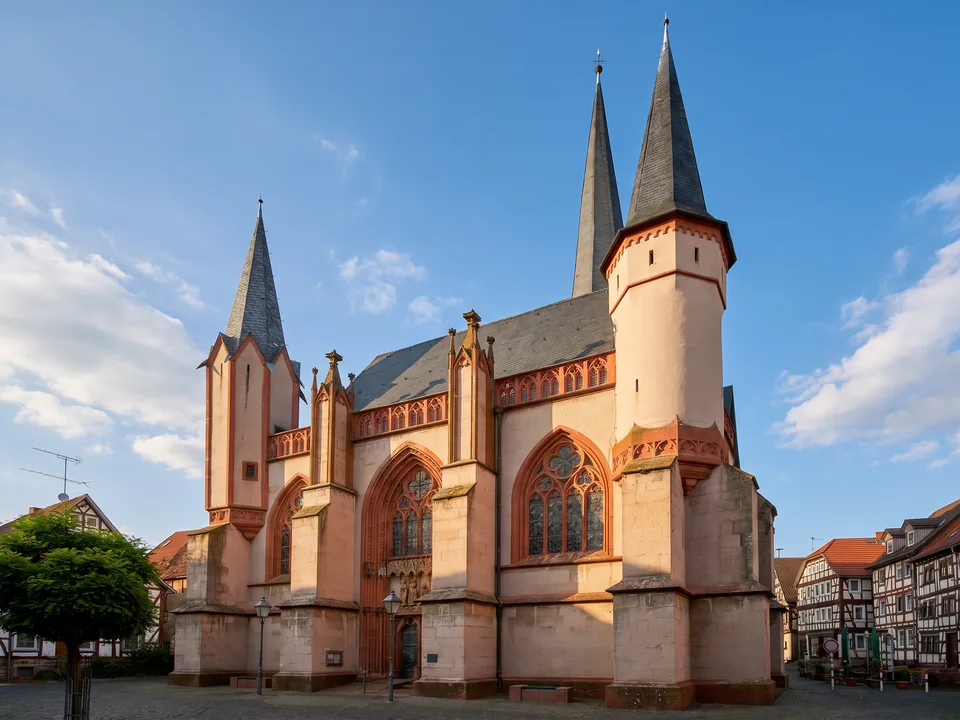 Gotische Liebfrauenkirche in Schotten mit zwei spitzen Türmen, rotem Sandstein und großen Maßwerkfenstern neben Fachwerkhäusern