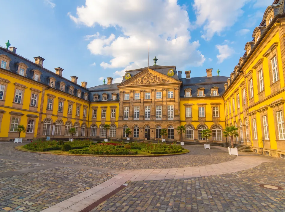 Gelbes barockes Residenzschloss Arolsen mit drei Flügeln und Ehrenhof unter blauem Himmel