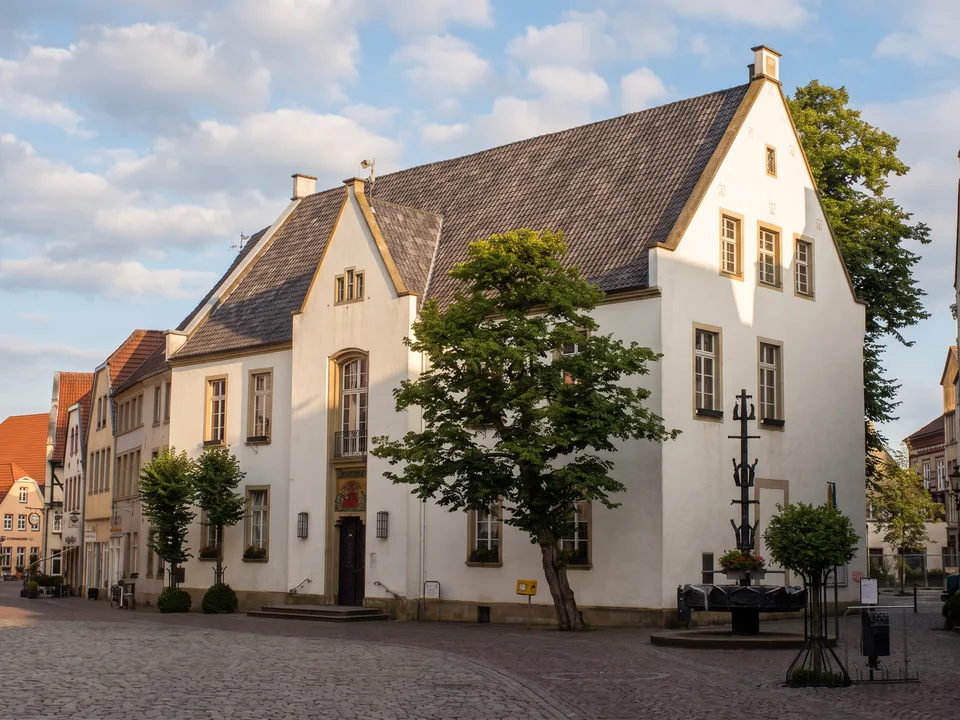 Das weiße Historische Rathaus am Marktplatz von Warendorf mit dunklem Schieferdach, Giebeln und Marktbrunnen