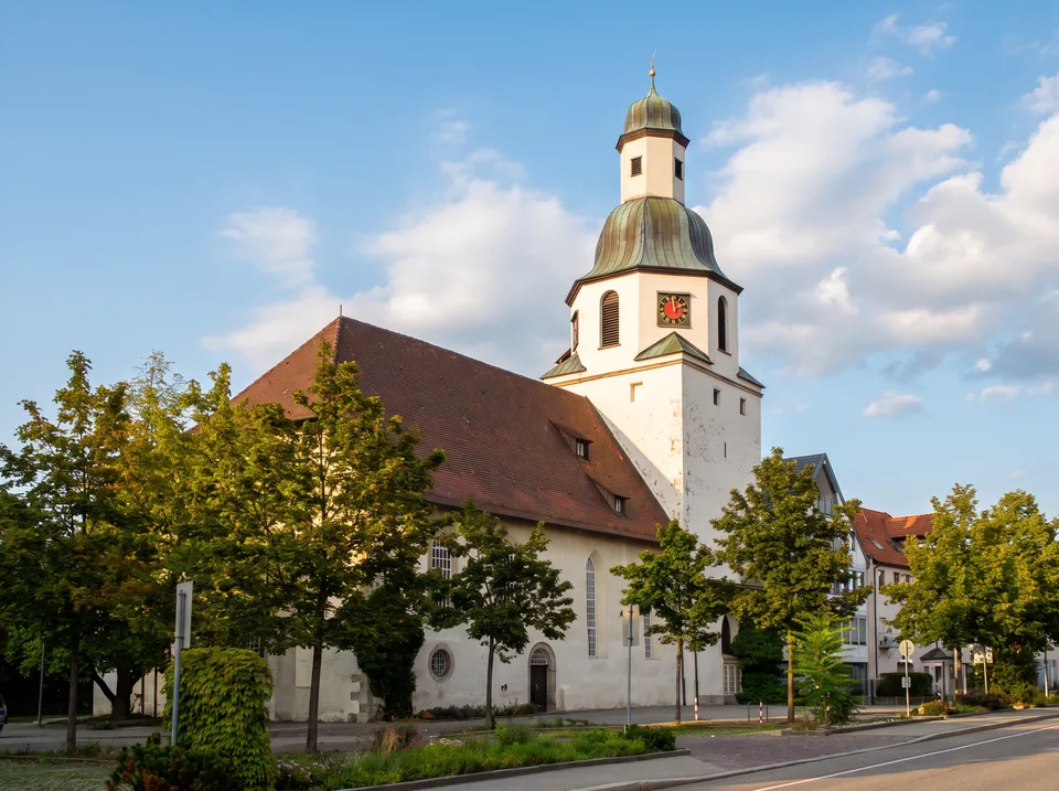 Die weiße Stadtkirche St. Bernhard in Winnenden mit Ziegeldach und Turm mit grüner glockenförmiger Kuppel und Laterne