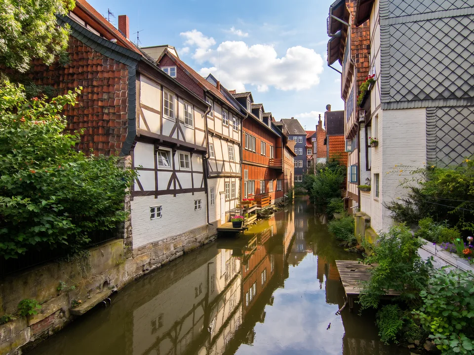Klein Venedig in Wolfenbüttel: schmaler Kanal zwischen alten Fachwerk- und Backsteinhäusern mit Spiegelungen im Wasser und grünen Pflanzen